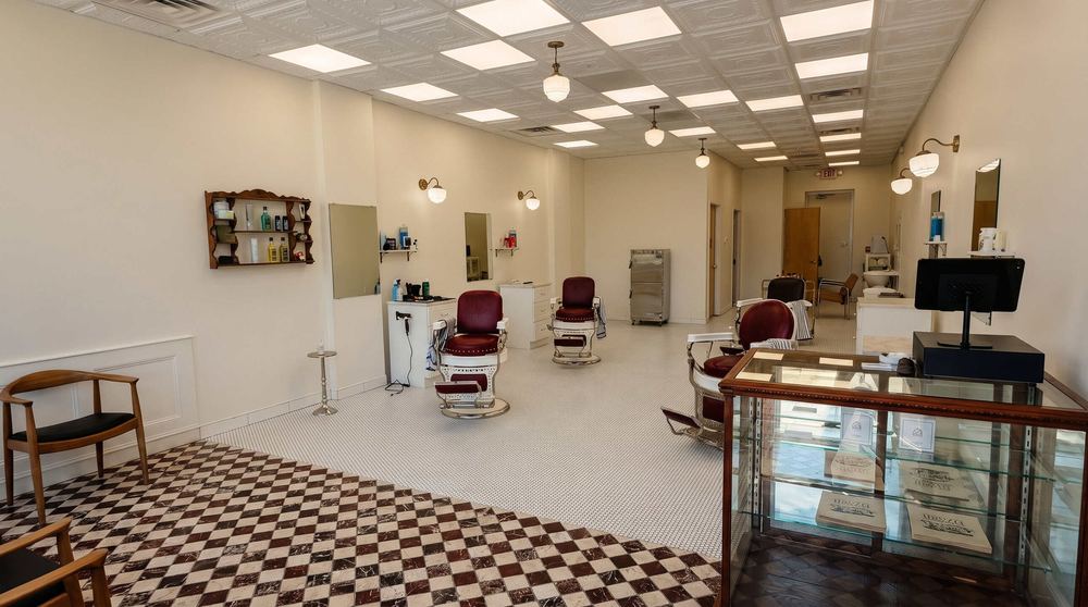 The main floor of Per Lui Barbershop, with vintage barber chairs, wall mirrors and a checkered tile entry.